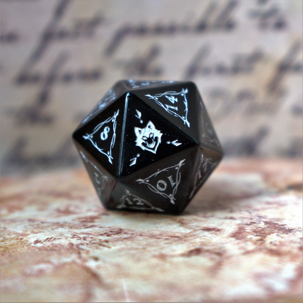 A set of black obsidian stone dnd ttrpg dice with engraved numbers, fangs and fine details, displayed on a textured surface with a blurred background.