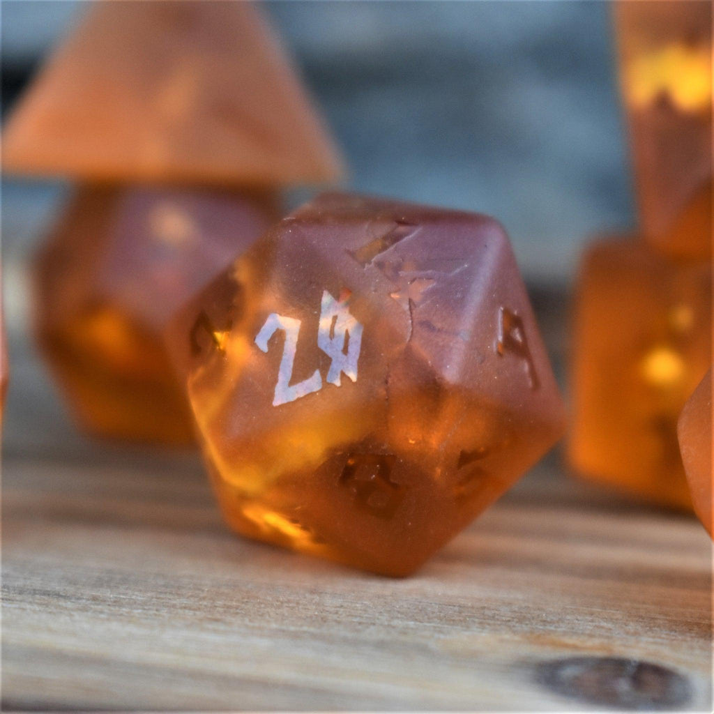 a set of 7 polyhedral dnd dice called Gates of Helheim Raised Lava Glass Dice on orange shattered matte glass with clear numbering. 