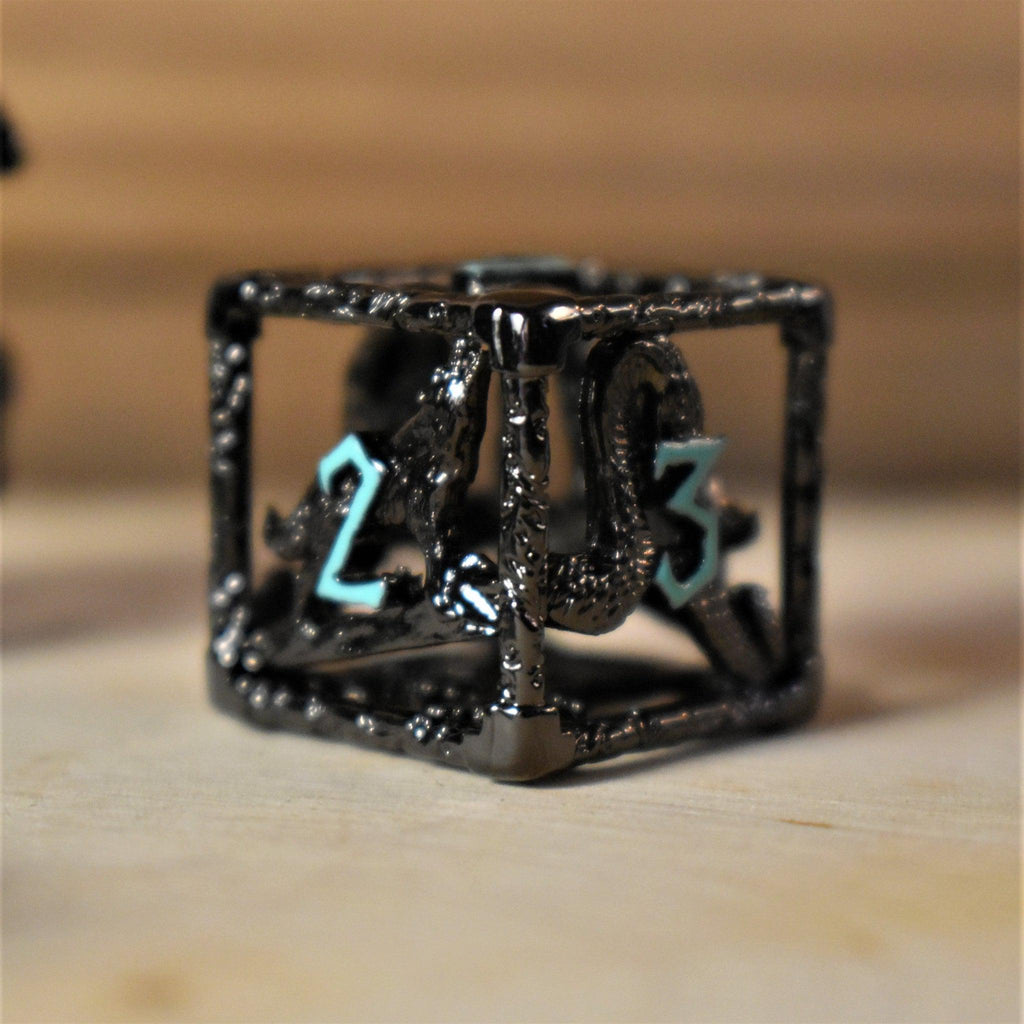 A set of hollow metal dice in black with blue embossed numbers, including various shapes such as a d4, d6, d8, d10, d12, and d20, displayed on a wooden surface.