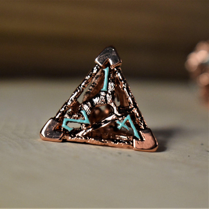 A set of copper-plated metal hollow dice with embossed numbers, including various shapes such as a D4, D6, D8, D10, D12, and D20, displayed on a wooden surface.