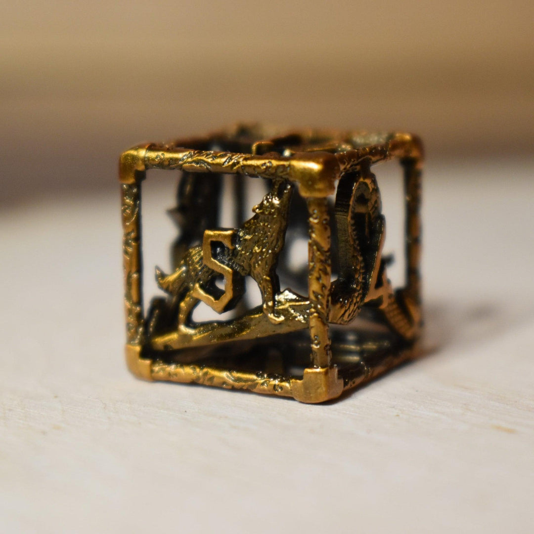 A set of golden brass hollow metal dice with embossed numbers, displayed on a wooden surface.