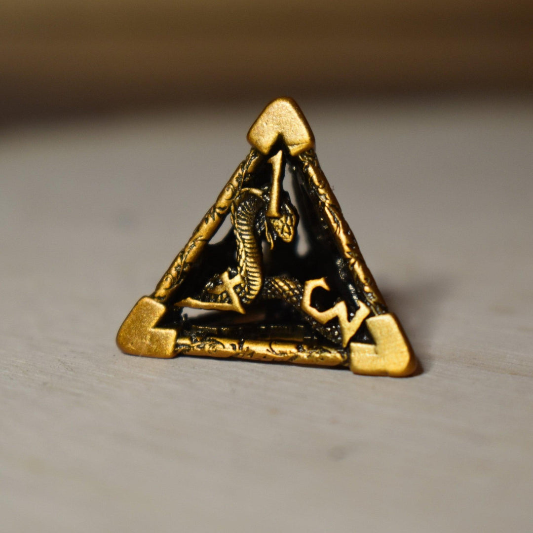 A set of golden brass hollow metal dice with embossed numbers, displayed on a wooden surface.