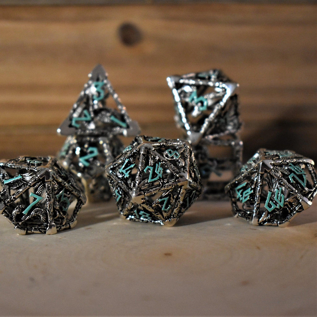 A set of silver and blue hollow metal dice with embossed numbers, displayed on a wooden surface.