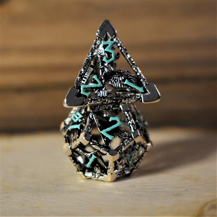 A set of silver and blue hollow metal dice with embossed numbers, displayed on a wooden surface.
