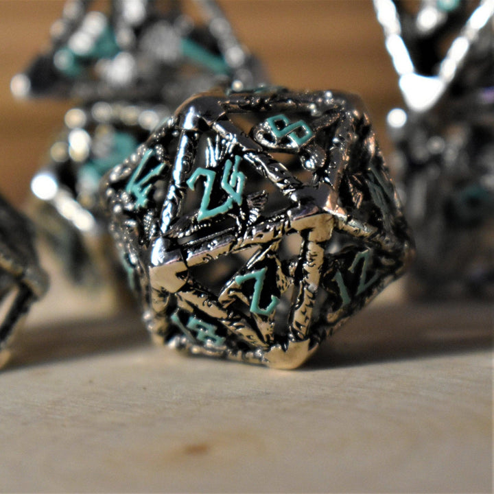 A set of silver and blue hollow metal dice with embossed numbers, displayed on a wooden surface.