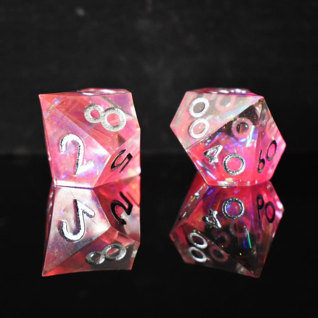 A set of sharp-edged, pink resin dnd dice with silver engraved numbers, reflecting a metallic sheen inside of each die