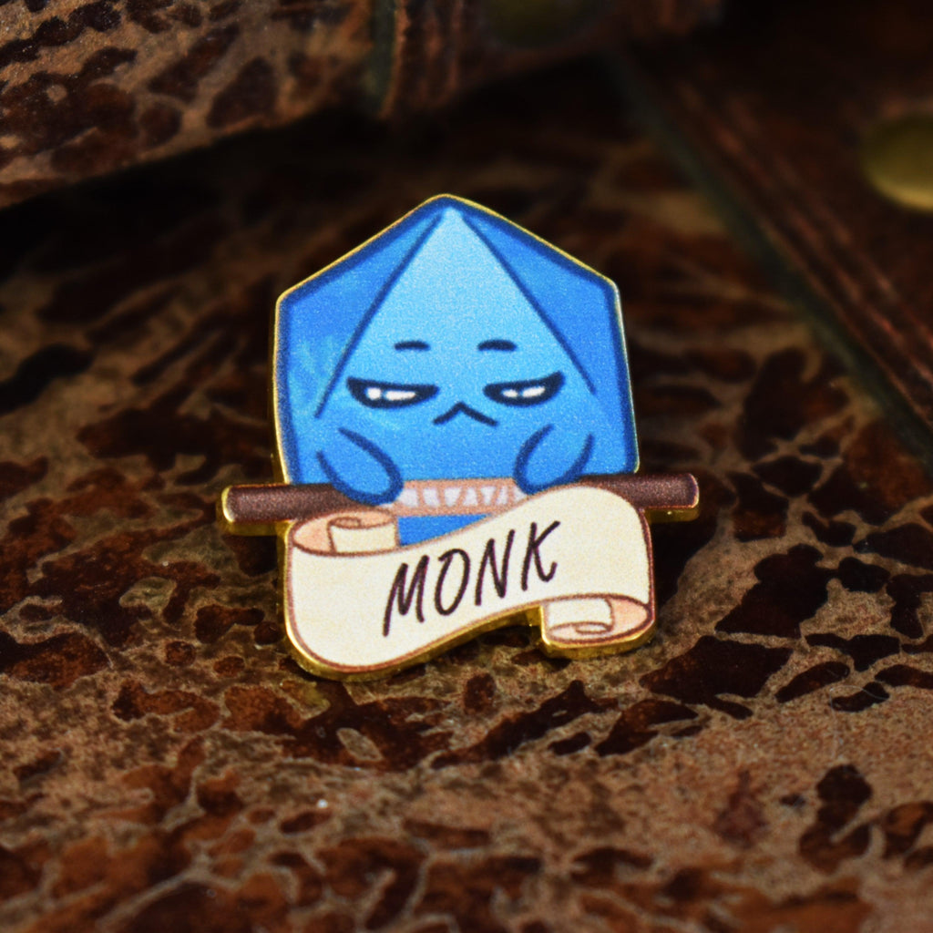 A pin with a blue dice character illustration labeled 'MONK' on a banner.