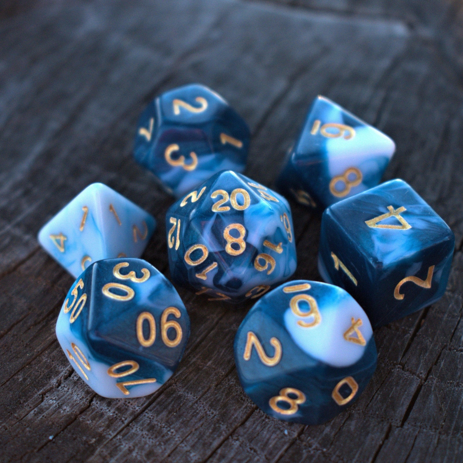 A set of blue acrylic dice with engraved numbers, displayed on a wooden surface.