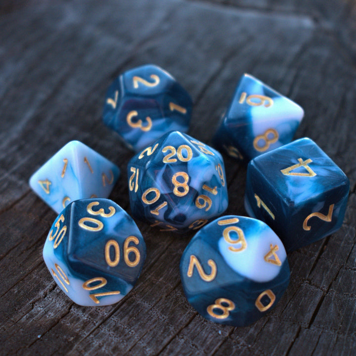 A set of blue acrylic dice with engraved numbers, displayed on a wooden surface.
