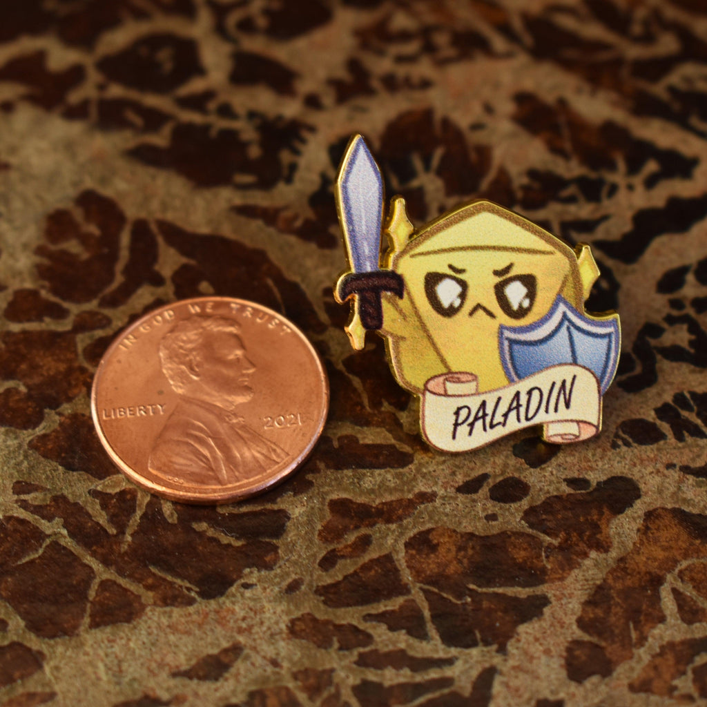 A colorful enamel pin featuring a paladin class character from D&D, with a sword and shield, displaying the word 'PALADIN' on a banner.
