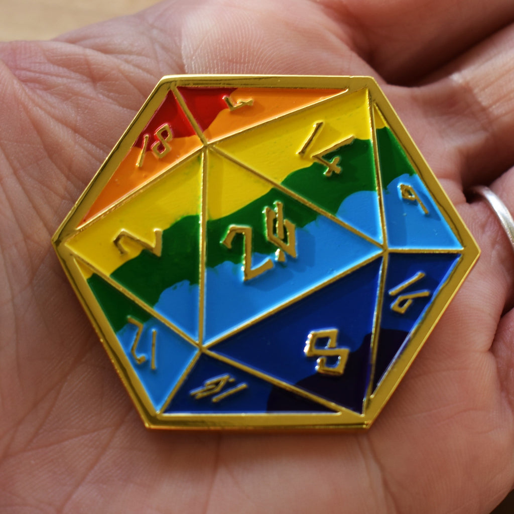 A colorful D20-shaped pin with gold trim, featuring numbers in someones hand
