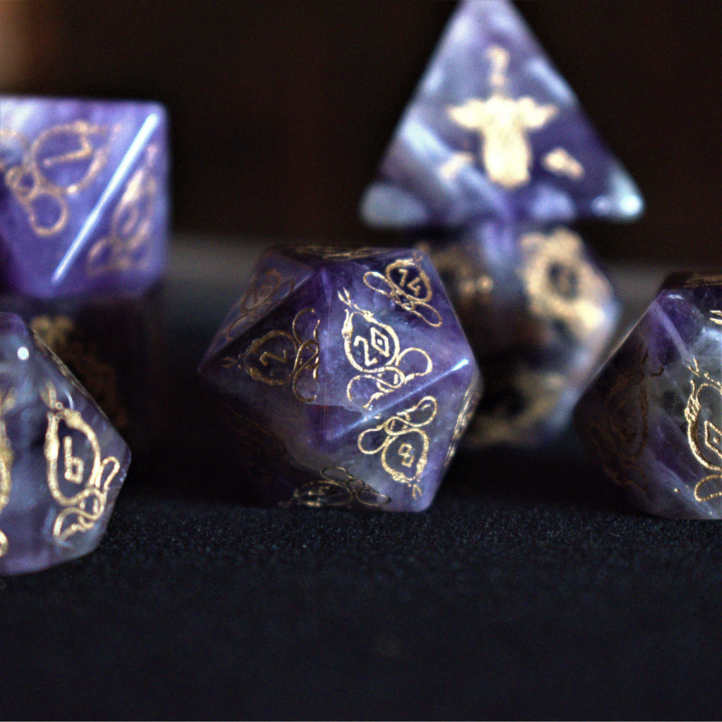 A set of viking inspired purple amethyst stone ttrpg dice with engraved numbers in gold