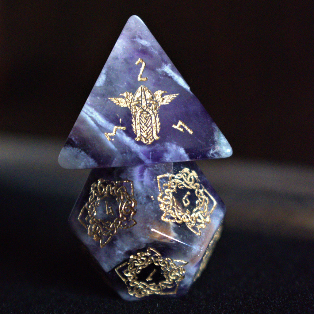 A set of viking inspired purple amethyst stone ttrpg dice with engraved numbers in gold