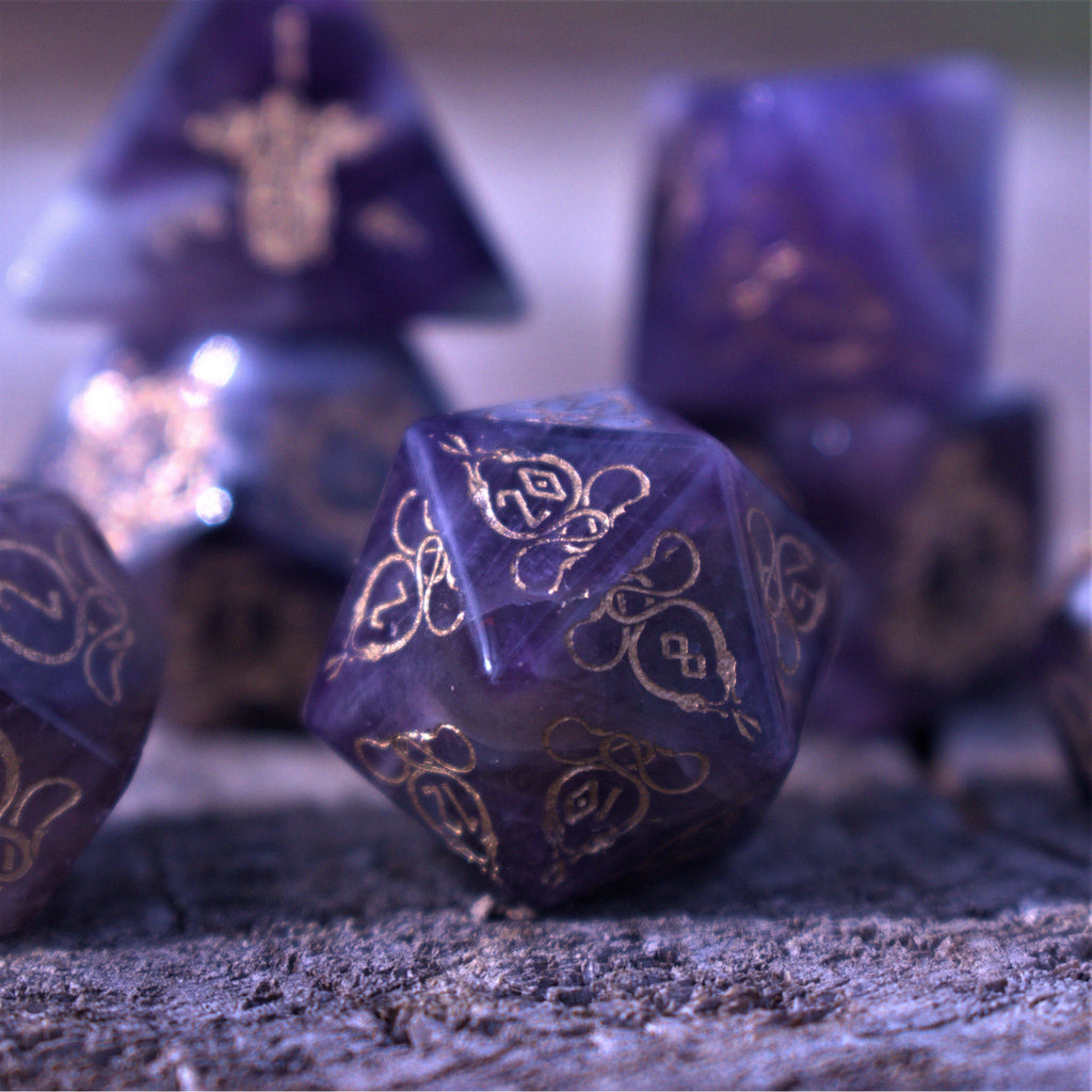 A set of viking inspired purple amethyst stone ttrpg dice with engraved numbers in gold