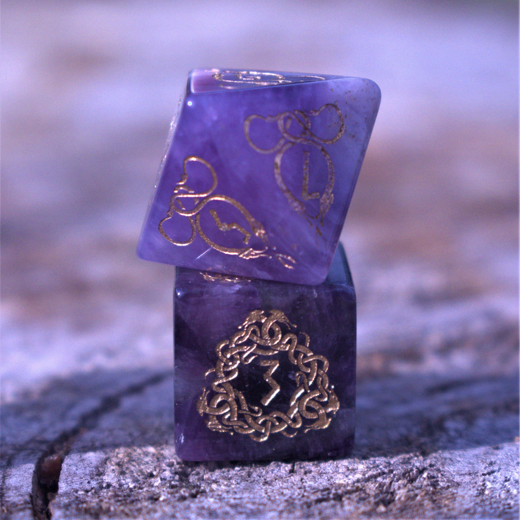 A set of viking inspired purple amethyst stone ttrpg dice with engraved numbers in gold