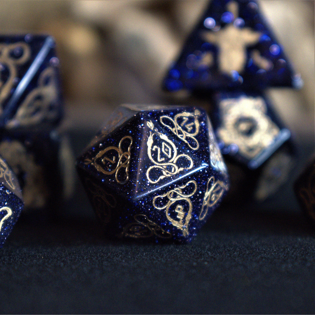A close-up of hand-carved viking inspired blue sandstone ttrpg dice with engraved numbers and designs in gold
