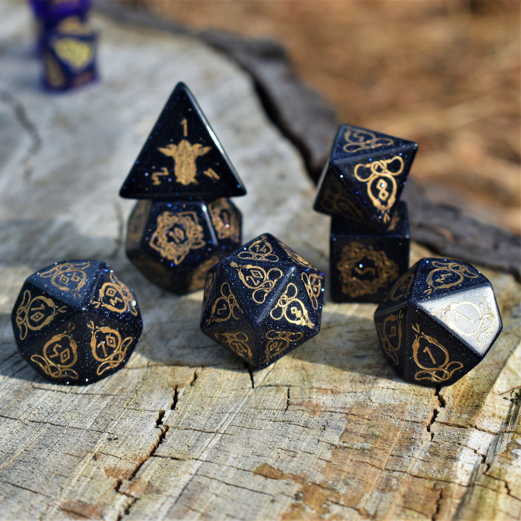A close-up of hand-carved viking inspired blue sandstone ttrpg dice with engraved numbers and designs in gold