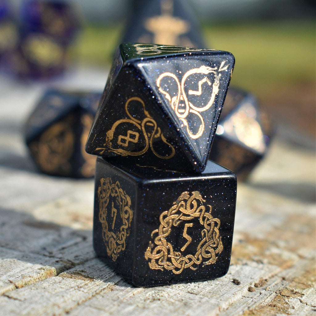 A close-up of hand-carved viking inspired blue sandstone ttrpg dice with engraved numbers and designs in gold