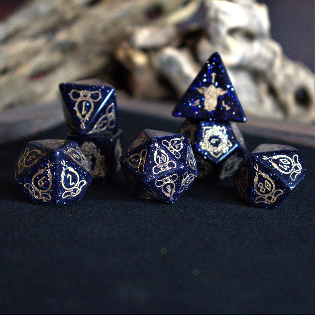 A close-up of hand-carved viking inspired blue sandstone ttrpg dice with engraved numbers and designs in gold