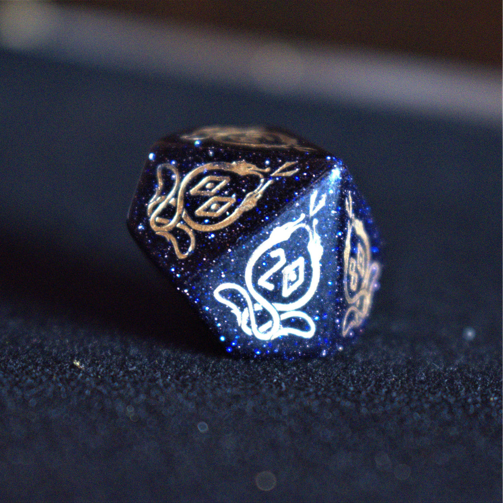 A close-up of hand-carved viking inspired blue sandstone ttrpg dice with engraved numbers and designs in gold