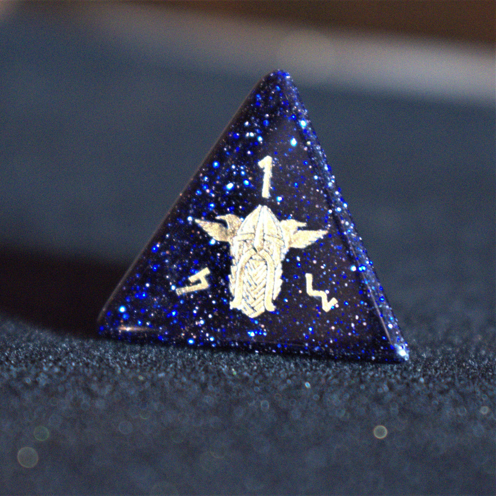A close-up of hand-carved viking inspired blue sandstone ttrpg dice with engraved numbers and designs in gold