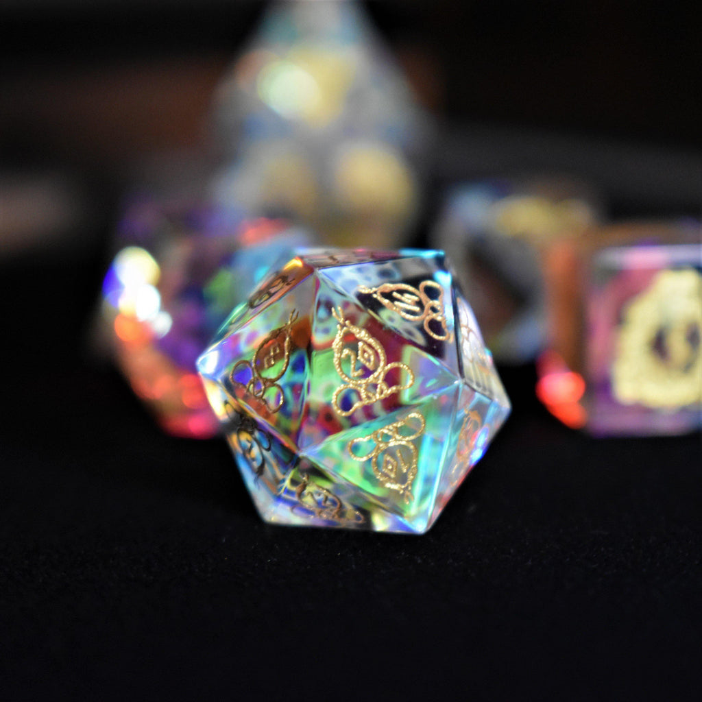 A set of hand-carved, iridescent prism glass dnd dice with engraved numbers, including a D4, D6, D8, two D10s, D12, and D20.