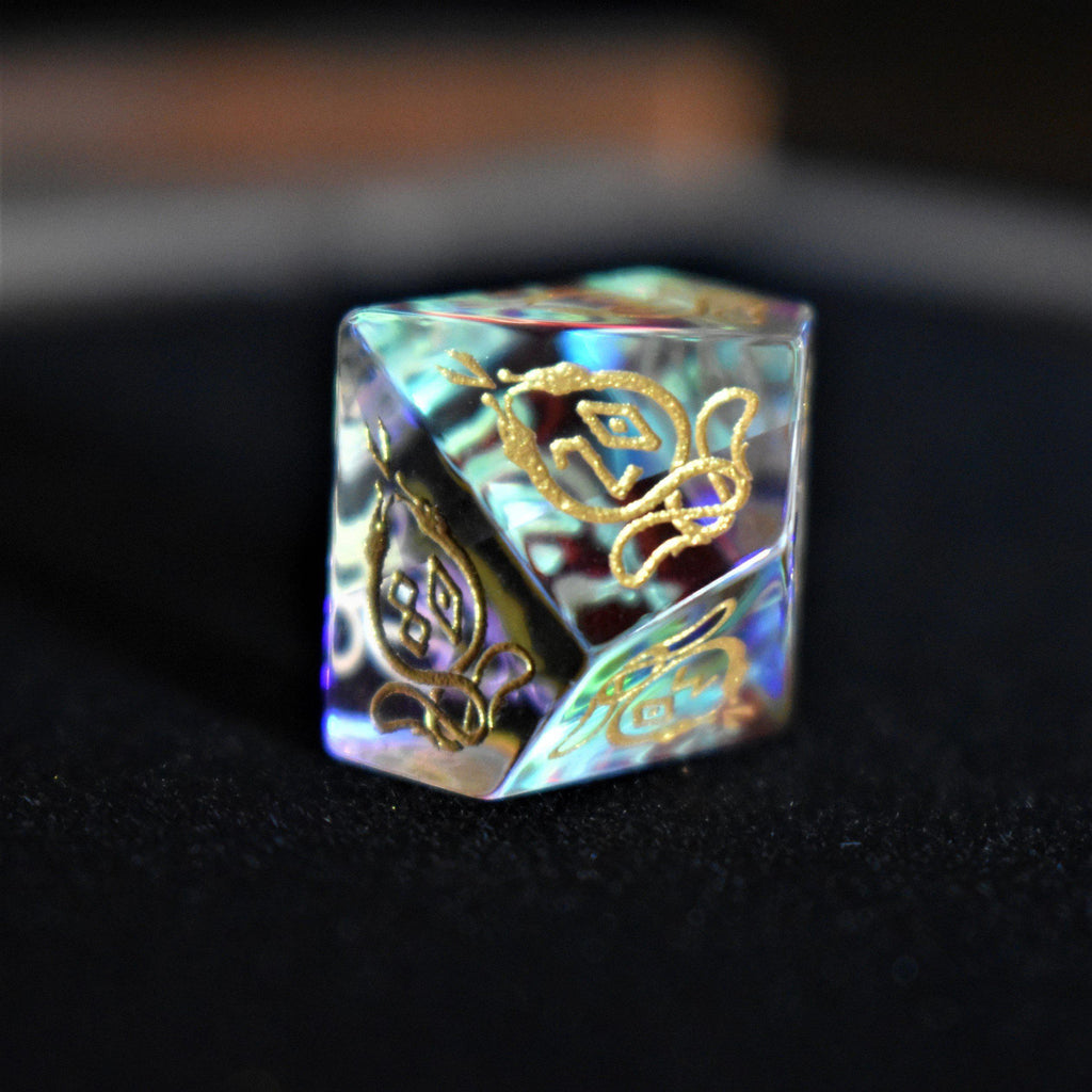 A set of hand-carved, iridescent prism glass dnd dice with engraved numbers, including a D4, D6, D8, two D10s, D12, and D20.