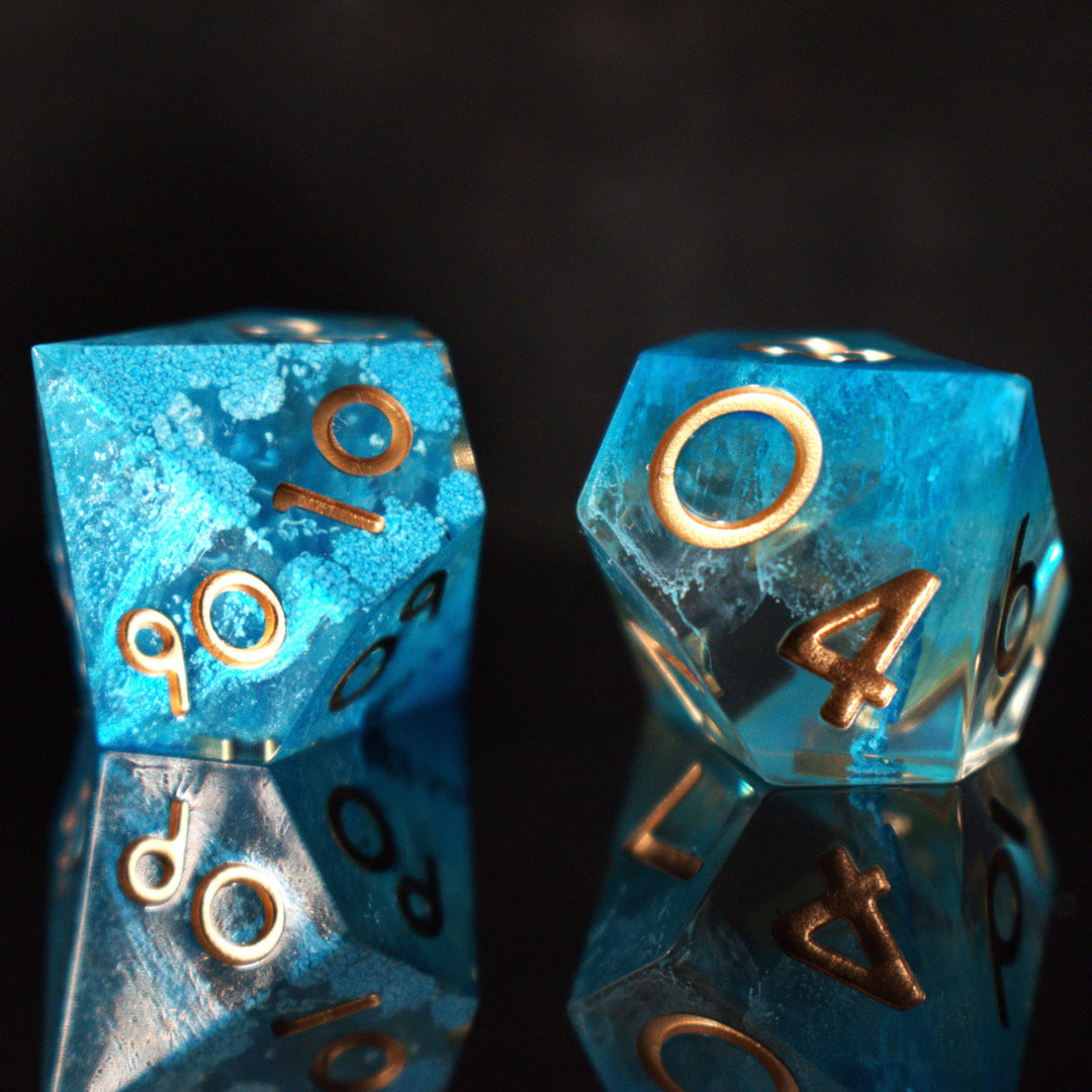 A set of sharp-edged resin dice in blue with gold numbers, including various shapes typical for RPG games.