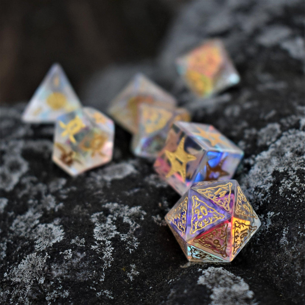 A set of hand-cut, multicolored prismatic glass polyhedral dice with engraved numbers and details inspired by the ocean on each face