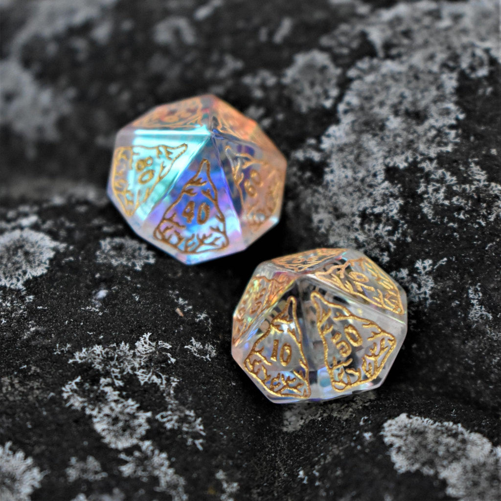 A set of hand-cut, multicolored prismatic glass polyhedral dice with engraved numbers and details inspired by the ocean on each face.