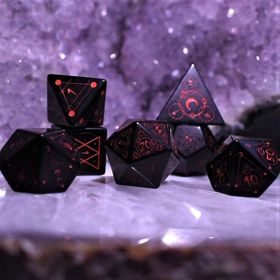 A set of Spellcaster Obsidian Stone polyhedral Dice with red engraved numbers and symbols