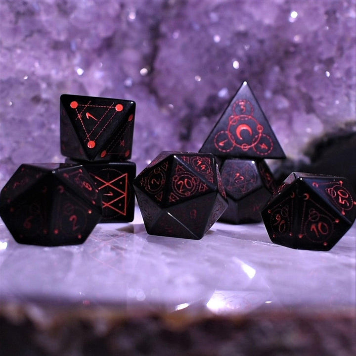 A set of Spellcaster Obsidian Stone polyhedral Dice with red engraved numbers and symbols