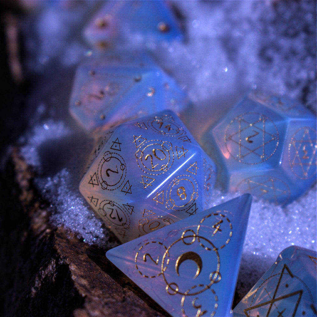 A set of hand-carved, Opalite gemstone dnd dice with engraved and golden hand-painted designs to create an iridescent spellcasting experience  