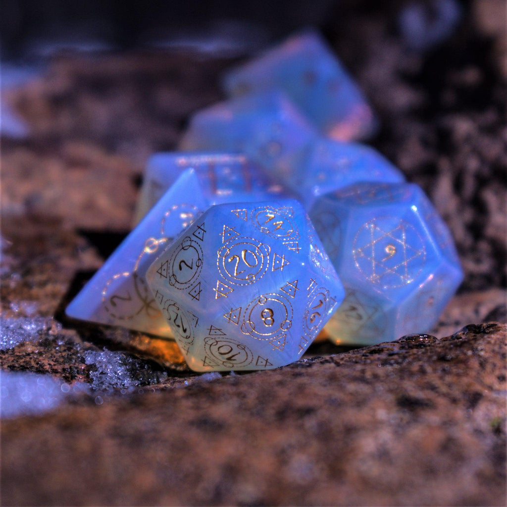 A set of hand-carved, Opalite gemstone dnd dice with engraved and golden hand-painted designs to create an iridescent spellcasting experience  
