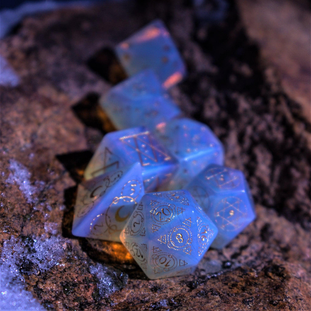 A set of hand-carved, Opalite gemstone dnd dice with engraved and golden hand-painted designs to create an iridescent spellcasting experience  