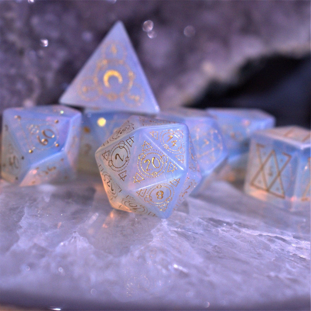 A set of hand-carved, Opalite gemstone dnd dice with engraved and golden hand-painted designs to create an iridescent spellcasting experience  