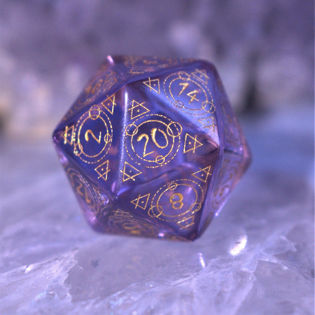 A set of purple glass dice with engraved golden numbering and details for tabletop gaming and collectors