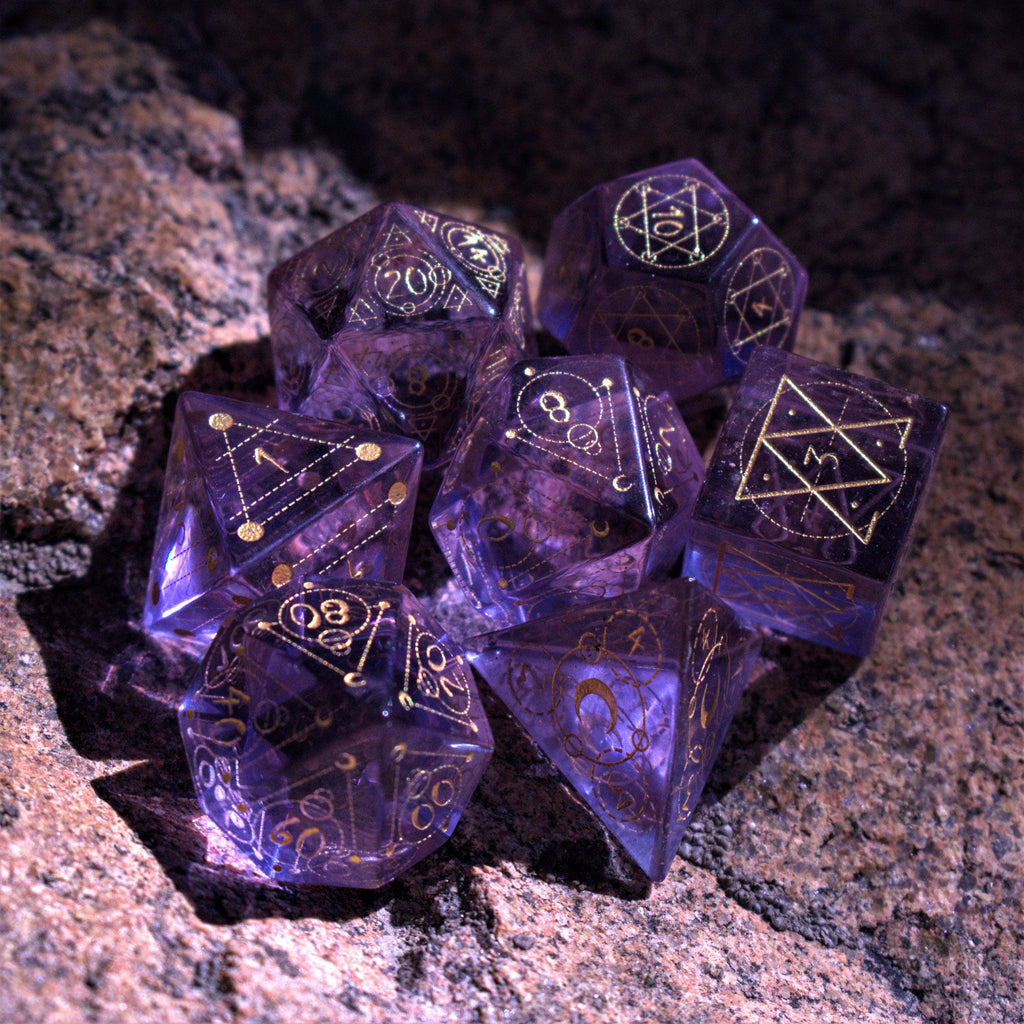 A set of purple glass dice with engraved golden numbering and details for tabletop gaming and collectors