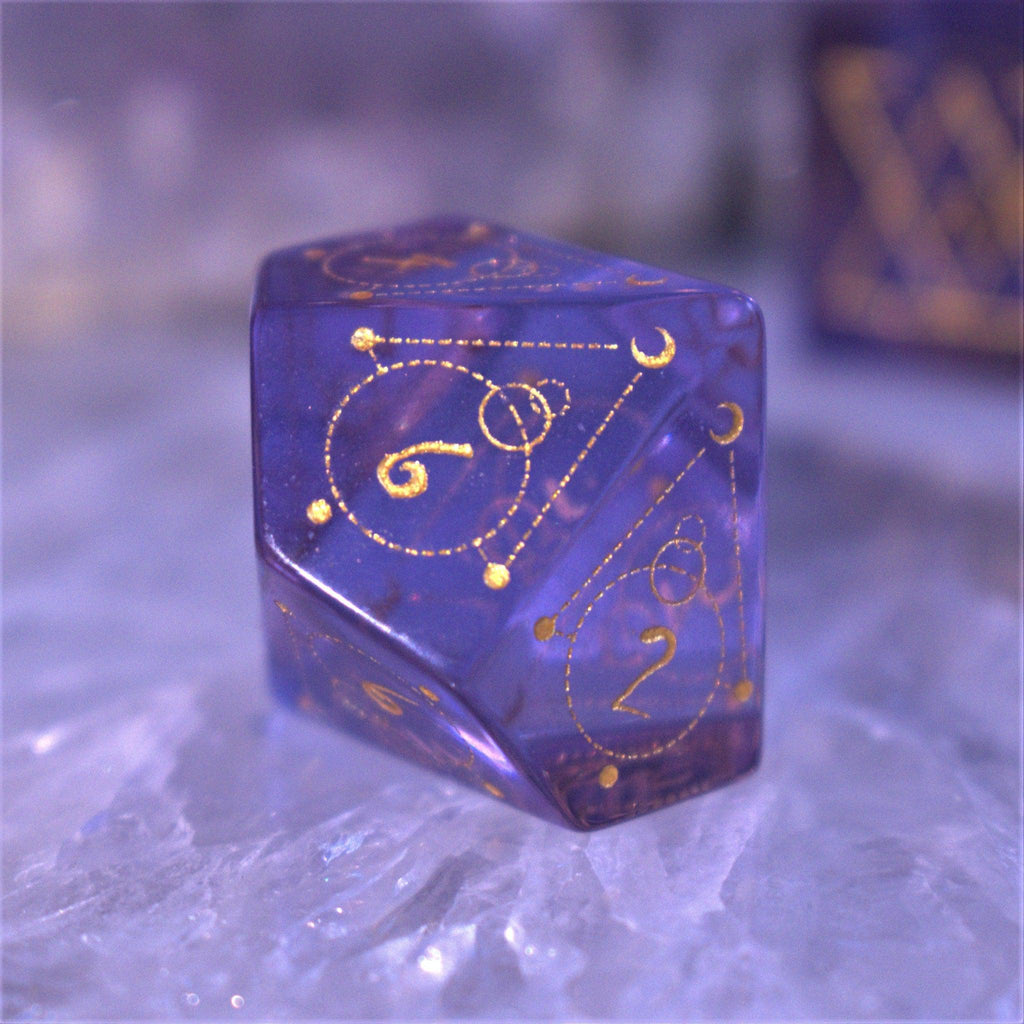 A set of purple glass dice with engraved golden numbering and details for tabletop gaming and collectors