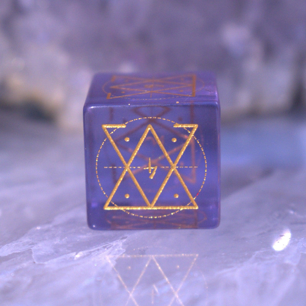 A set of purple glass dice with engraved golden numbering and details for tabletop gaming and collectors