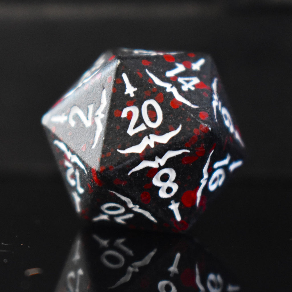 A set of black metal polyhedral dice with blood splatter across them and white numbering and sword details for tabletop gaming and board games