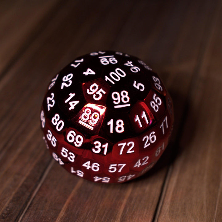 A large red metal d100 dice with white numbers on a wooden surface.