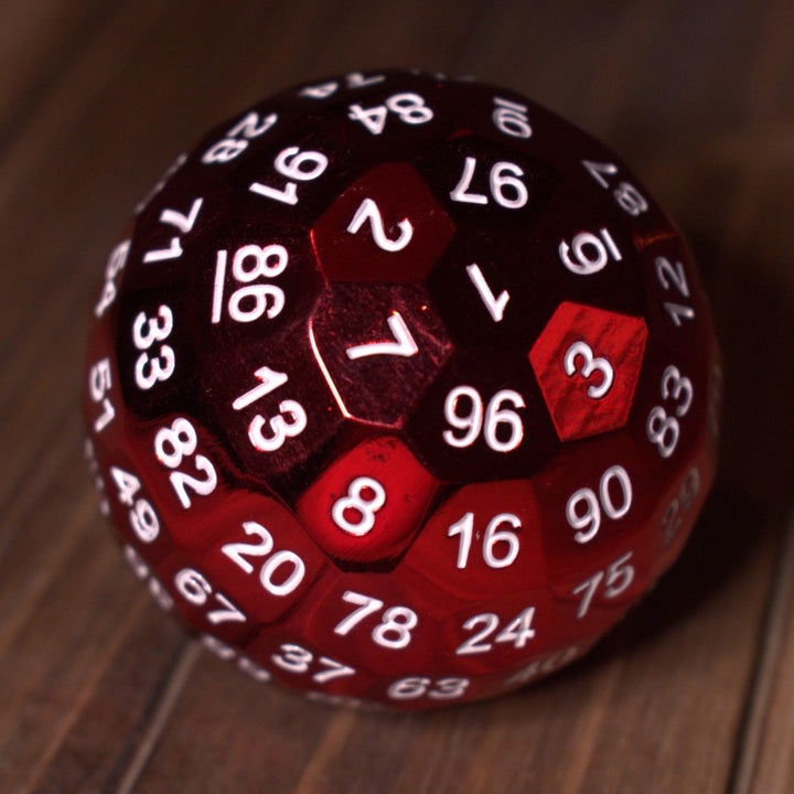 A large red metal d100 dice with white numbers on a wooden surface.