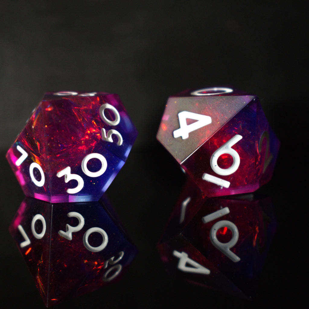 A set of sharp-edged resin dice in pink and purple colors with engraved white numbers, reflecting on a shiny surface.