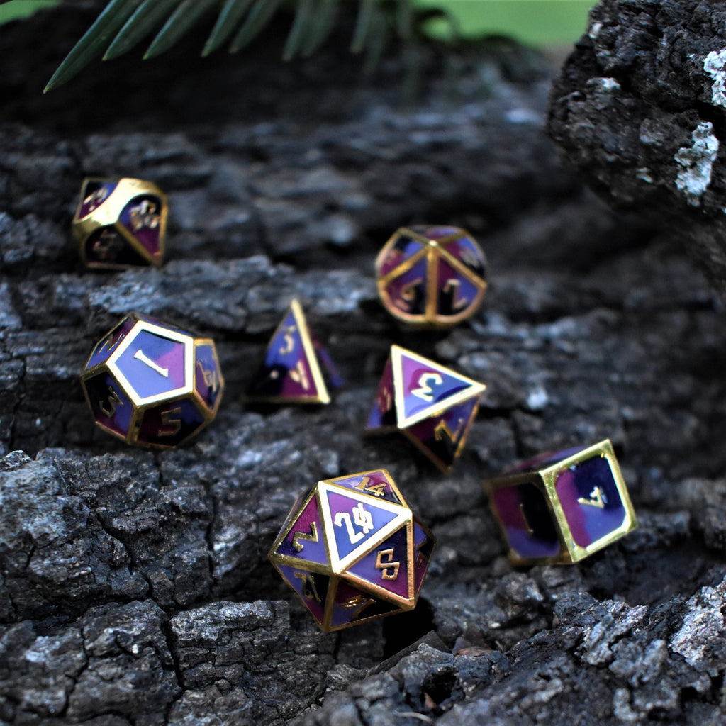 A set of metal dice that are different hues of purple with gold numbers and border for tabletop gaming and board games
