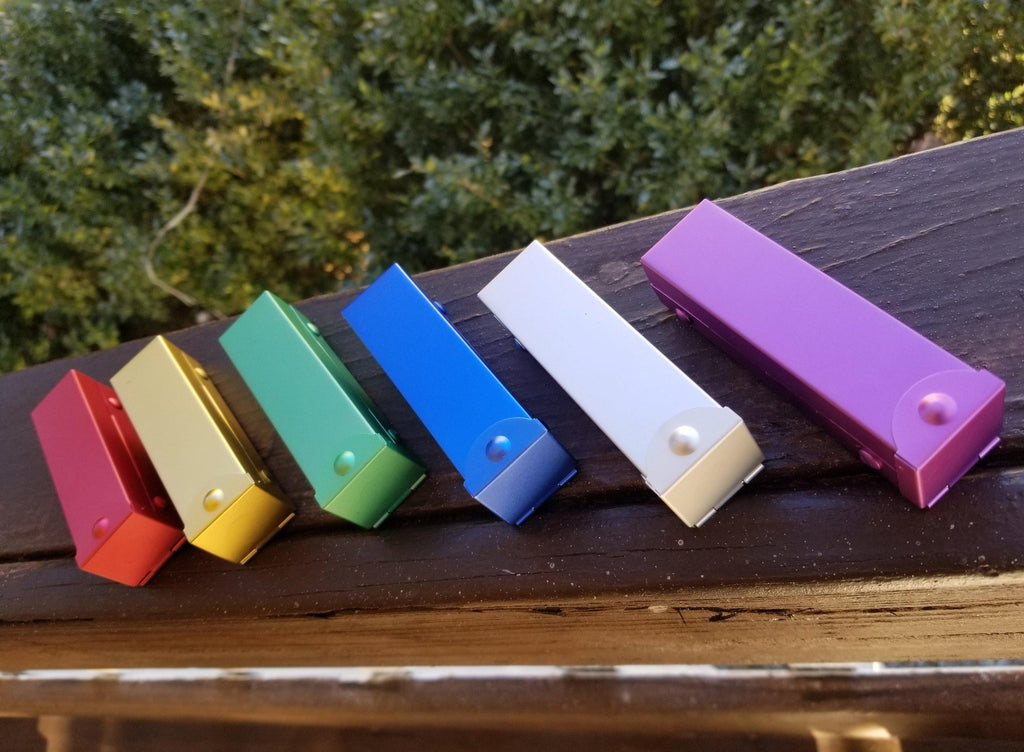 six metal d6 dice cases in red, gold, green, blue, silver and purple