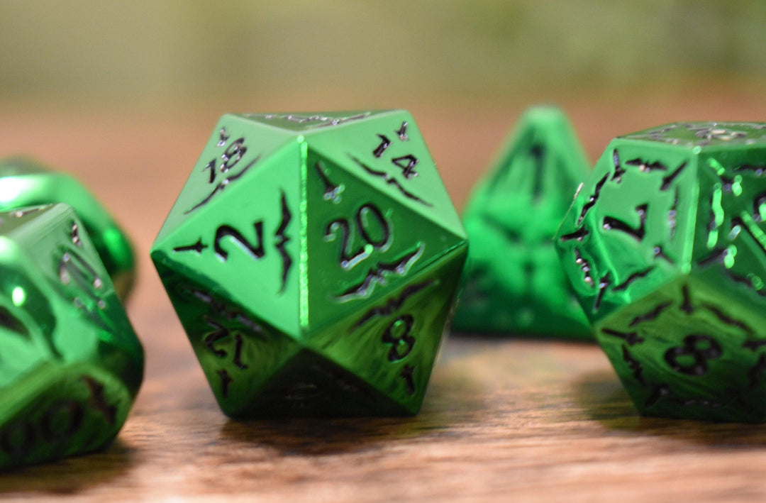 A set of solid metal green metallic dnd polyhedral dice with black numbering and sword details for tabletop gaming and board games